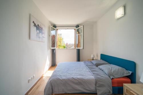 Un dormitorio con una cama azul y una ventana en Le Rosier - 20 min de Paris et d'Orly, en Vitry-sur-Seine