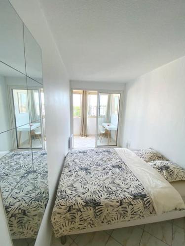 une chambre blanche avec un lit et un miroir dans l'établissement Appartement spacieux 65M2, avec piscine et parking, à Fréjus