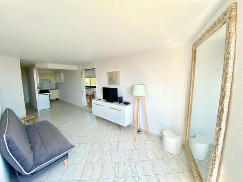 a living room with a couch and a mirror at Appartement spacieux 65M2, avec piscine et parking in Fréjus