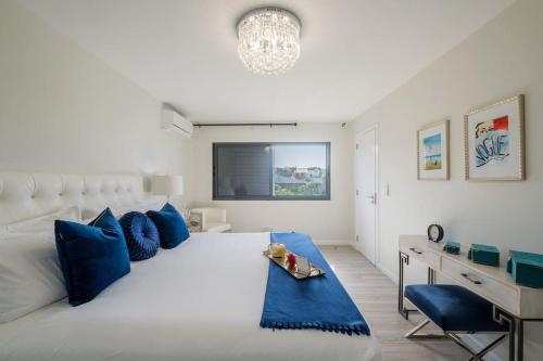 a bedroom with a white bed with blue pillows and a desk at Don Jose Ocean View Heated Pool in Lagoa