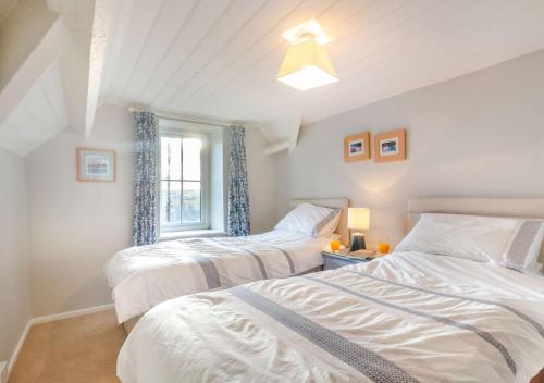 a bedroom with two beds and a window at Bryn Siriol Cottage in Abersoch