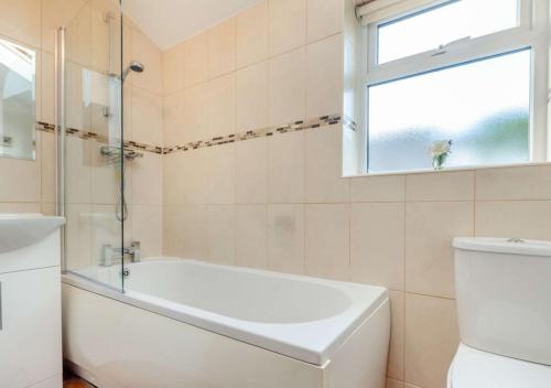 a bathroom with a tub and a toilet and a window at Bryn Siriol Cottage in Abersoch