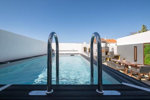 a swimming pool with two metal rails next to a house at Don Jose Ocean View Heated Pool in Lagoa