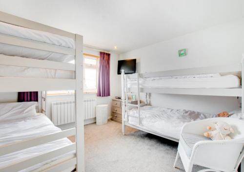 a bedroom with two bunk beds and a chair at Kookaburra in Abersoch