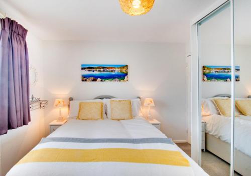 a white bedroom with a bed and two lamps at Kookaburra in Abersoch