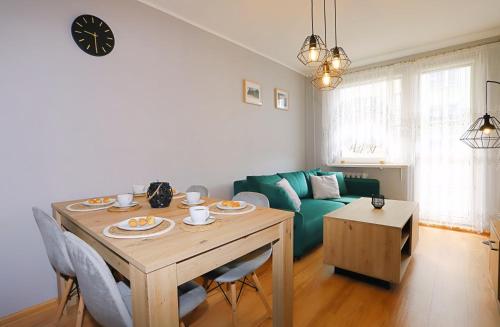 sala de estar con mesa y sofá verde en Apartament Zielony Dąb, en Wałbrzych
