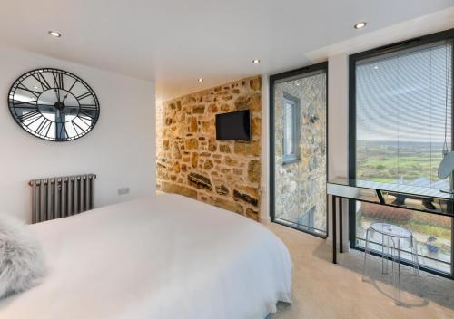 a bedroom with a large bed and a clock on the wall at 1 Fron Dirion in Llanbedrog