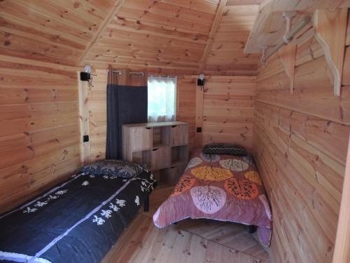 2 camas en una cabaña con paredes de madera en CHALET ATYPIQUE LOLA type KOTA location en gîte, en Chazemais