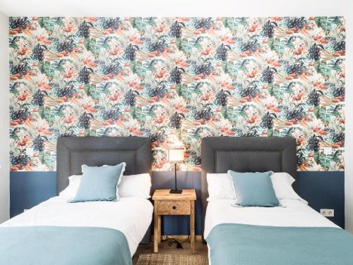 2 Betten in einem Schlafzimmer mit Blumentapete in der Unterkunft Almar Collection Atocha in Madrid