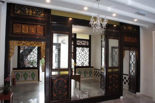 Habitación con puertas de madera y lámpara de araña. en Heeren Palm Suites en Melaka