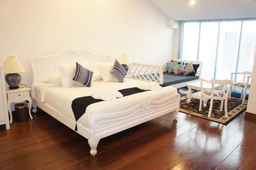 um quarto com uma cama branca, uma mesa e cadeiras em Heeren Palm Suites em Malaca