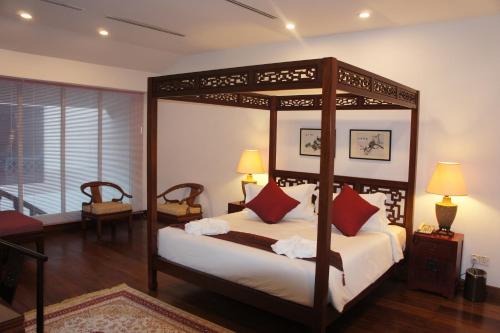 a bedroom with a canopy bed with red pillows at Heeren Palm Suites in Melaka