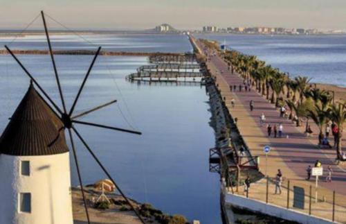 a beach with a windmill and a lighthouse in the water at Mar Menor in San Pedro del Pinatar