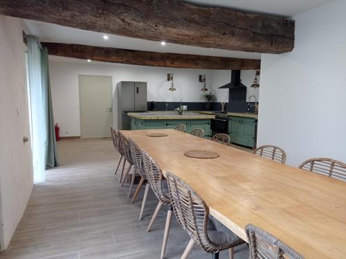 une cuisine avec une grande table et des chaises en bois dans l'établissement Gîte Oust Au LIt, à Saint-Vincent-sur-Oust