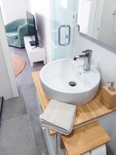 a bathroom with a white sink and a tv on a counter at Beach & City - Trafaria in Trafaria