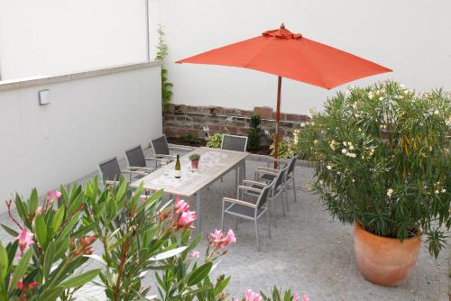 a patio with a table and an umbrella and chairs at Gästehaus Vogler in Heuchelheim-Klingen