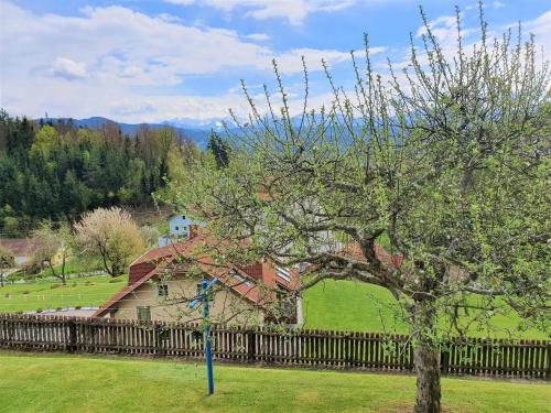 a tree in front of a house with a fence at Apartment by Wörthersee with Pool in Karnten
