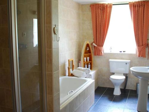 een badkamer met een bad, een toilet en een wastafel bij Nice cottage in Sainte-Marguerite-d'Elle with garden in Sainte-Marguerite-dʼElle
