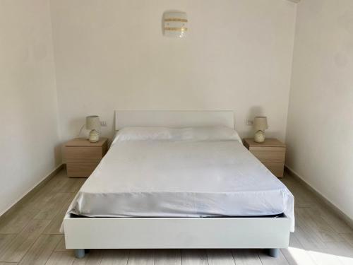 - un lit blanc dans une chambre avec 2 tables de nuit dans l'établissement Villetta 6 La Caletta, à La Caletta