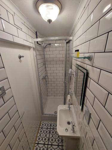 baño blanco con ducha y lavamanos en Westfield House en Blackpool
