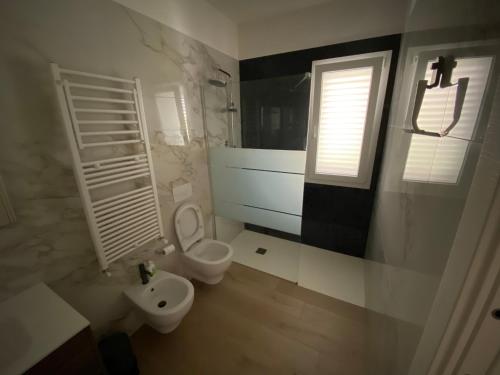 baño con aseo y lavabo y ventana en TOT apartment, en Policoro