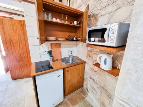 a small kitchen with a sink and a microwave at Aphrodite's Pool Retreat in Skarinou