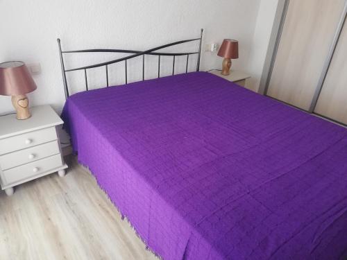 een slaapkamer met een paars bed en 2 nachtkastjes bij Mimosa LOCDENIA in Els Poblets