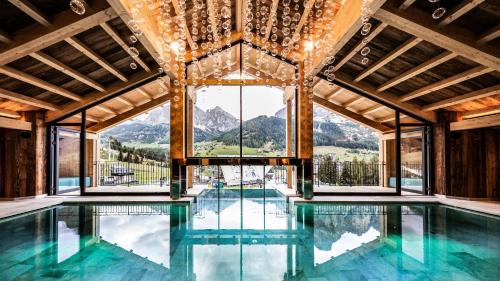 an indoor swimming pool with a large window and mountains at Hotel Arkadia - "Adults Only" in Corvara in Badia