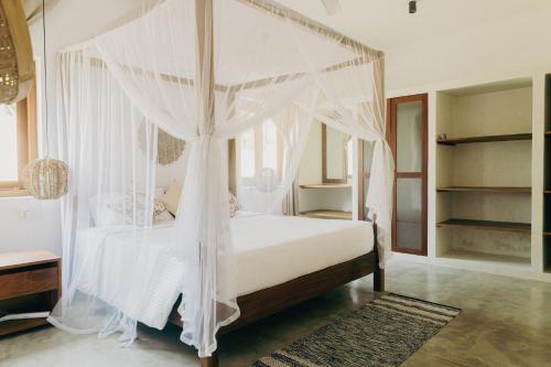 a bedroom with a canopy bed with white curtains at Ocean Divine Villa in Kalametiya