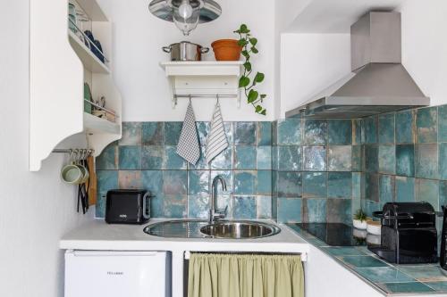 a small kitchen with a sink and blue tiles at Cath's Loft in Skopelos Town