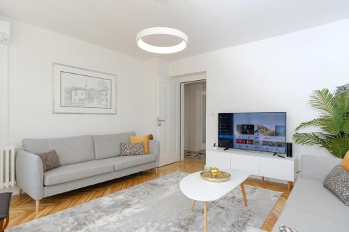 a living room with a couch and a tv at Apartment Skopljak + free garage in Sarajevo