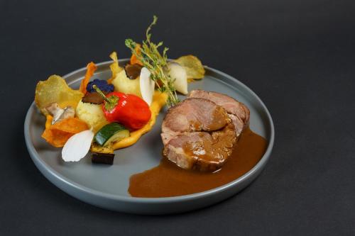 a plate of food with meat and vegetables on a table at Logis Le Grand Hotel in Château-du-Loir