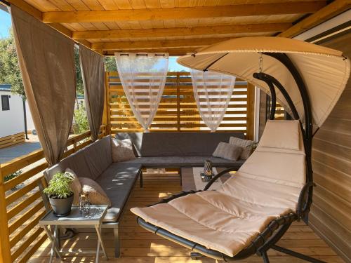 a porch with a couch and an umbrella at Mobile Home Saky, Camp Soline in Biograd na Moru