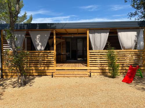 ein Haus mit einer Holzterrasse mit einer roten Tasche davor in der Unterkunft Mobile Home Saky, Camp Soline in Biograd na Moru