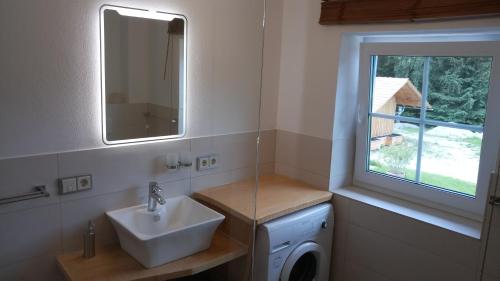 a bathroom with a sink and a mirror and a window at Ferienhaus Damberg in Übersee