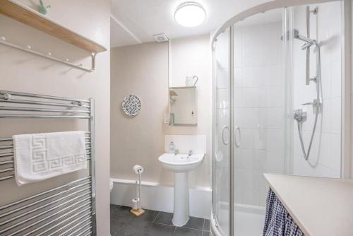a white bathroom with a sink and a shower at 8 The Craighurst in Southwold