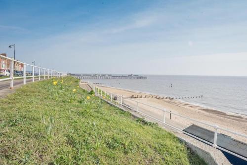 a beach with a fence and the ocean and a pier at 8 The Craighurst, Southwold in Southwold