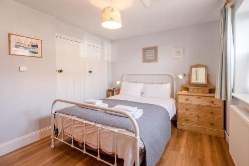 a bedroom with a bed and a dresser with a mirror at 8 The Craighurst, Southwold in Southwold