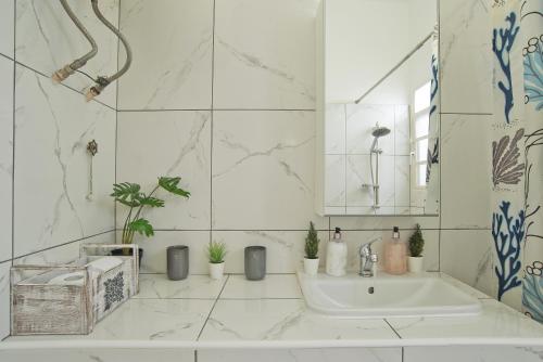 La salle de bains blanche est pourvue d'un lavabo et d'un miroir. dans l'établissement Andromaxi near SNFCC, à Athènes
