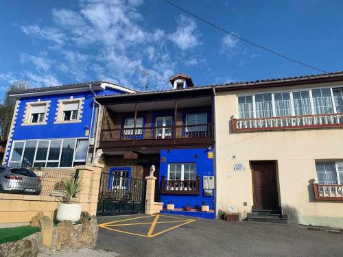 a blue and white building with a car parked in front at La Casina de Martín in Limanes