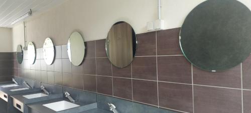 uma casa de banho com três lavatórios e espelhos na parede em Camping les Sables em Tournon-sur-Rhône