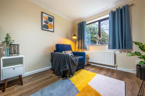 sala de estar con silla azul y TV en Grange Studio Apartment - Heathrow, en Londres