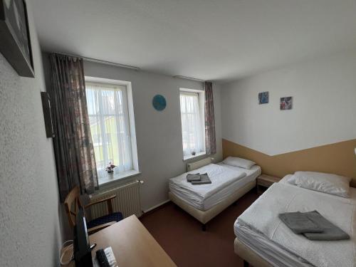 a small room with two beds and two windows at Pension zur Bergbahn in Lichtenhain