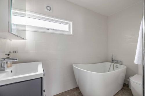 een witte badkamer met een bad en een wastafel bij Central Windsor, 5 mins to Legoland, Driveway in Windsor