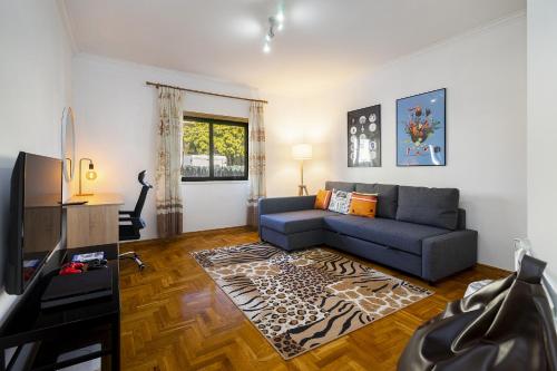 a living room with a blue couch and a television at WHome Perfect Family Hideout Residence w/AC & 4BR + 5BA in Cascais