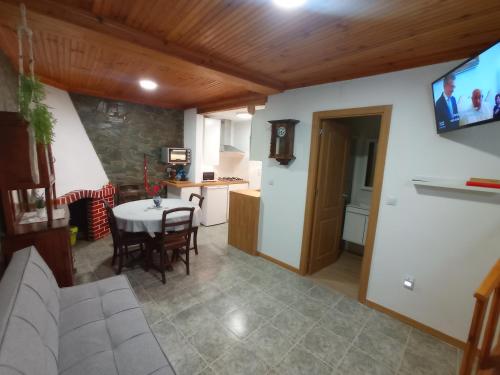 sala de estar y cocina con mesa y TV en Casa Rústica da Lavandeira, en Valongo dos Azeites