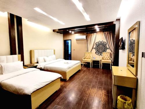 een hotelkamer met 2 bedden en 2 stoelen bij Hotel Visit Inn Executive in Lahore