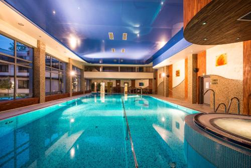 a large swimming pool in a building with a tub at Hotel Prezydent Krynica Zdrój in Krynica Zdrój