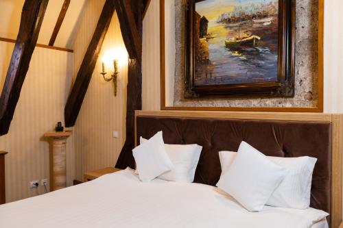 a bedroom with a white bed with a painting on the wall at Hotel Am Ring in Sibiu