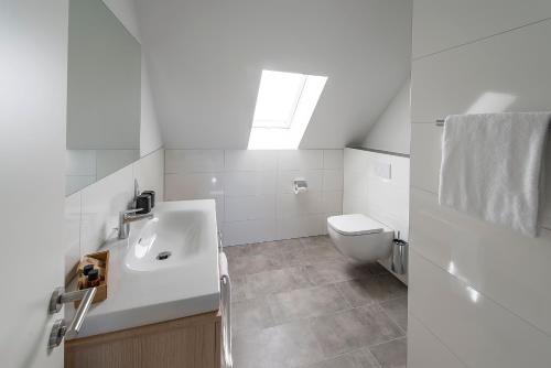 a white bathroom with a sink and a toilet at 1860 hotel im dinkelhaus in Neuenhaus